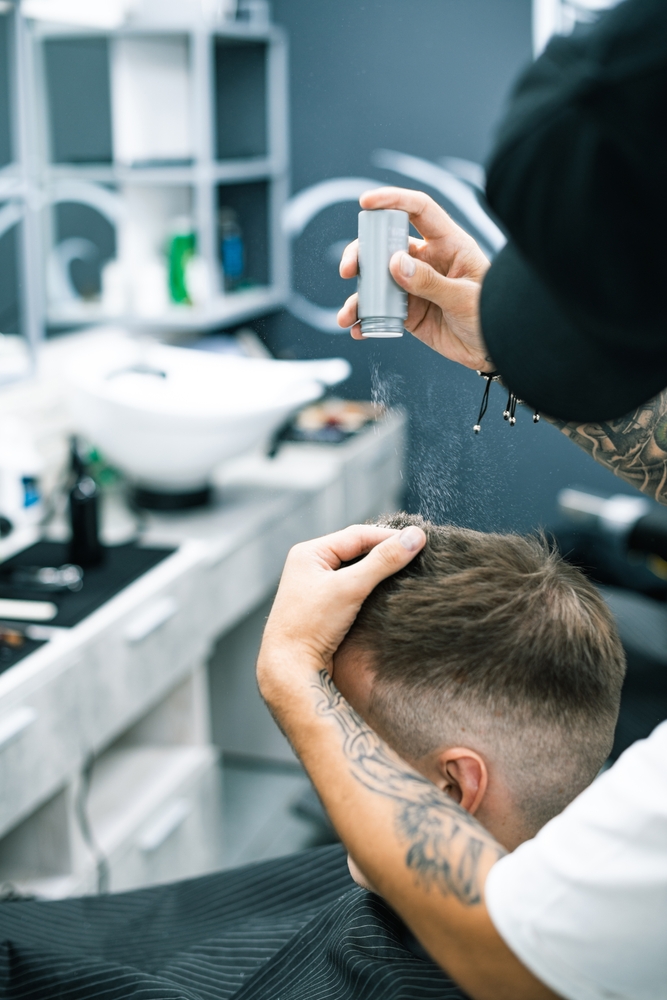 Tattooed,Hairdresser,Pouring,Hair,Volumizer,On,Client,During,Hairstyling,In