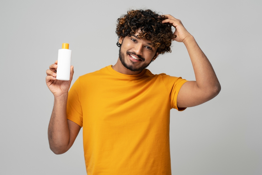 Smiling,Attractive,Indian,Man,Holding,A,White,Bottle,Of,Moisturizing